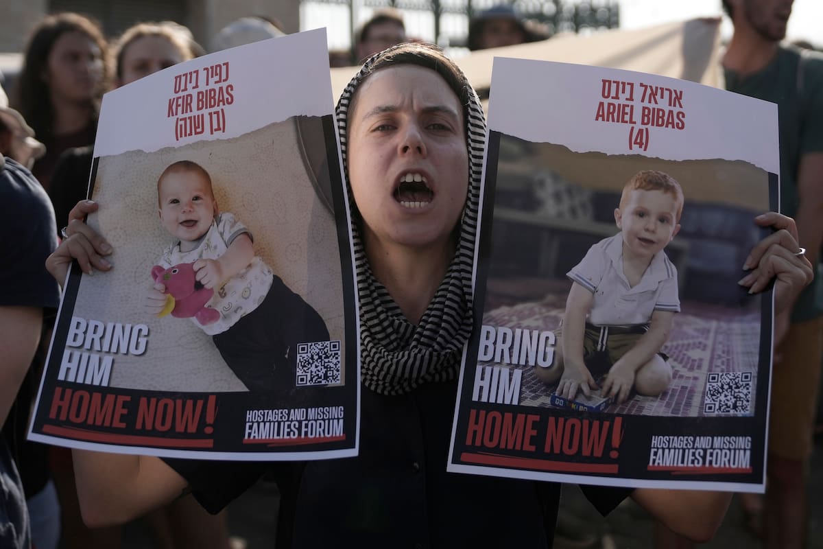 Una mujer sostiene carteles de Kfir y Ariel Bibas, cautivos de Hamás junto con sus padres en la Gaza, durante una marcha hacia la Knesset, el Parlamento de Israel, para pedir un acuerdo para liberar a los rehenes, en Jerusalén, el jueves 13 de junio de 2024.