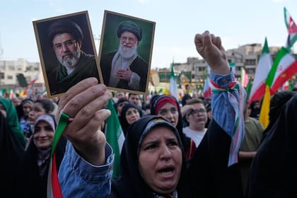 Una mujer sostiene imágenes del líder supremo iraní, el ayatollah Mojtaba Khamenei, y su padre, el asesinado Ali Khamenei, en una marcha en Teherán