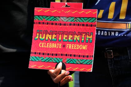 Una mujer sostiene un cartel antes de un partido de béisbol entre los Orioles de Baltimore y los Cachorros de Chicago, en Chicago, el domingo 18 de junio de 2023