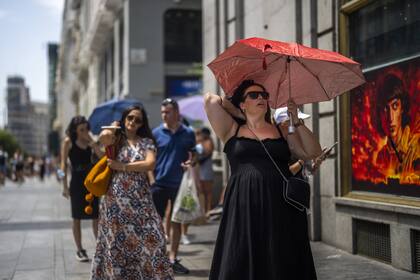 Una mujer sostiene un paraguas para protegerse del sol durante un caluroso día soleado en Madrid, España, el lunes 18 de julio de 2022