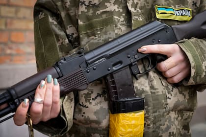 Una mujer sostiene un rifle de asalto Kalashnikov mientras patrulla una calle vacía en Kyiv, Ucrania