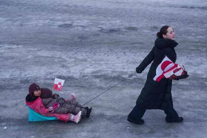 Una mujer tira de sus hijos en un trineo durante una protesta contra la política del presidente estadounidense Donald Trump hacia Groenlandia frente al consulado estadounidense en Nuuk, Groenlandia, el sábado 17 de enero de 2026. (AP Photo/Evgeniy Maloletka)