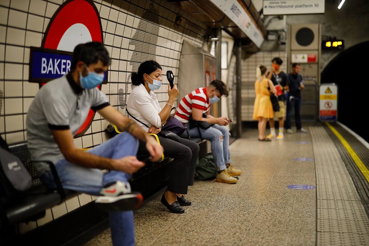 Una mujer usa un ventilador portátil para enfriarse en una plataforma de la estación de metro de Londres el 31 de julio de 2020