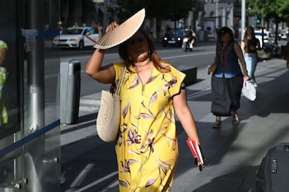 Una mujer usando un abanico para protegerse del sol, en Madrid