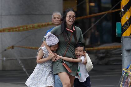 Una mujer y sus hijos batallan contra el viento generado por el tifón Haikui en Taipei, Taiwán,