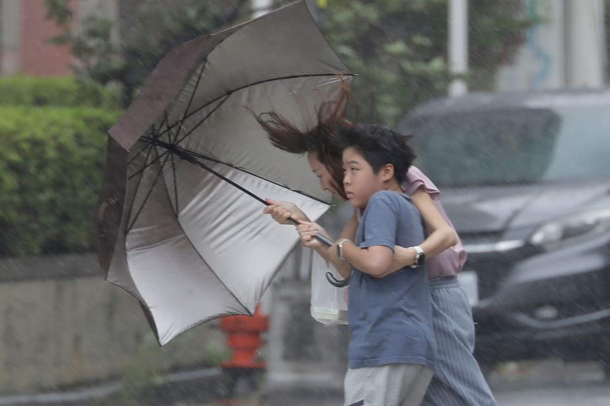 Una mujer y un niño avanzan entre la lluvia provocada por el tifón Bavi, el sábado 11 de julio de 2026, en Taichung, Taiwán. (AP Foto/Chiang Ying-ying)