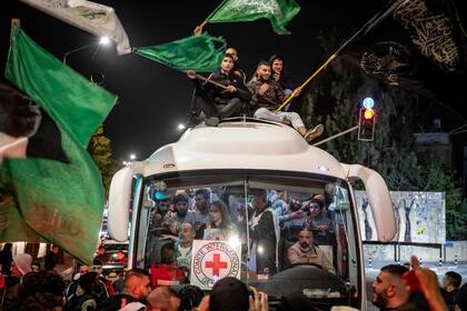 Una multitud rodea un autobús de la Cruz Roja que transporta presos palestinos liberados de cárceles israelíes a cambio de rehenes liberados por Hamás de la Franja de Gaza, en Ramallah, en la Cisjordania ocupada, el 26 de noviembre de 2023.