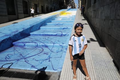 Una nena posa con la camiseta argentina frente a la obra de Segatori en el microcentro porteño