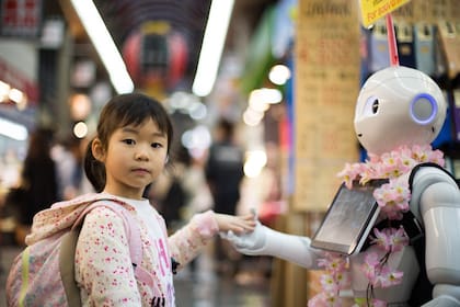 Una nena saluda a un robot Pepper
