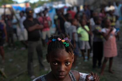 Una niña espera con otras víctimas del sismo de magnitud 7,2 que sacudió Haití la semana pasada en un centro de distribución de alimentos en Les Cayes, el sábado 21 de agosto de 2021. (AP Foto/Matias Delacroix)