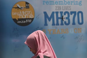 Una niña está parada junto a un mensaje de condolencias durante el Día de Conmemoración para el evento del vuelo MH370 en Kuala Lumpur, Malasia, el domingo 3 de marzo de 2019. (AP Foto/Vincent Thian, Archivo)