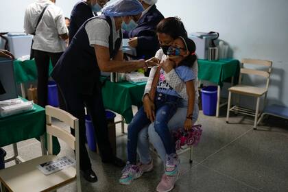 Una niña llora al ser vacunada durante una campaña de inoculación contra el polio, la rubeola y la influenza organizada por el Ministerio de Salud de Venezuela en Caracas el 18 de junio del 2022. El país, sin embargo, carece de varias vacunas y tiene una de las tasas de inoculación de menores más bajas del mundo, según un estudio de la Associated Press.  (AP Photo/Ariana Cubillos)