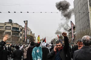 Una nube de humo se asoma detrás de una manifestación en Teherán