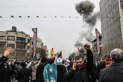 Una nube de humo se asoma detrás de una manifestación en Teherán