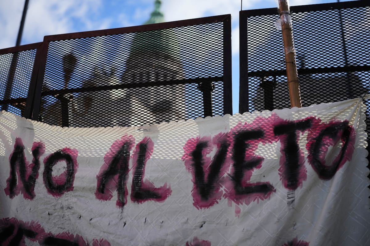 Una pancarta con el mensaje "No al veto" cuelga de una valla frente al Congreso