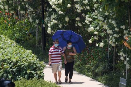 Una pareja con máscaras, en medio de la preocupación por la propagación del nuevo coronavirus, camina por un parque en Singapur el 24 de marzo de 2020