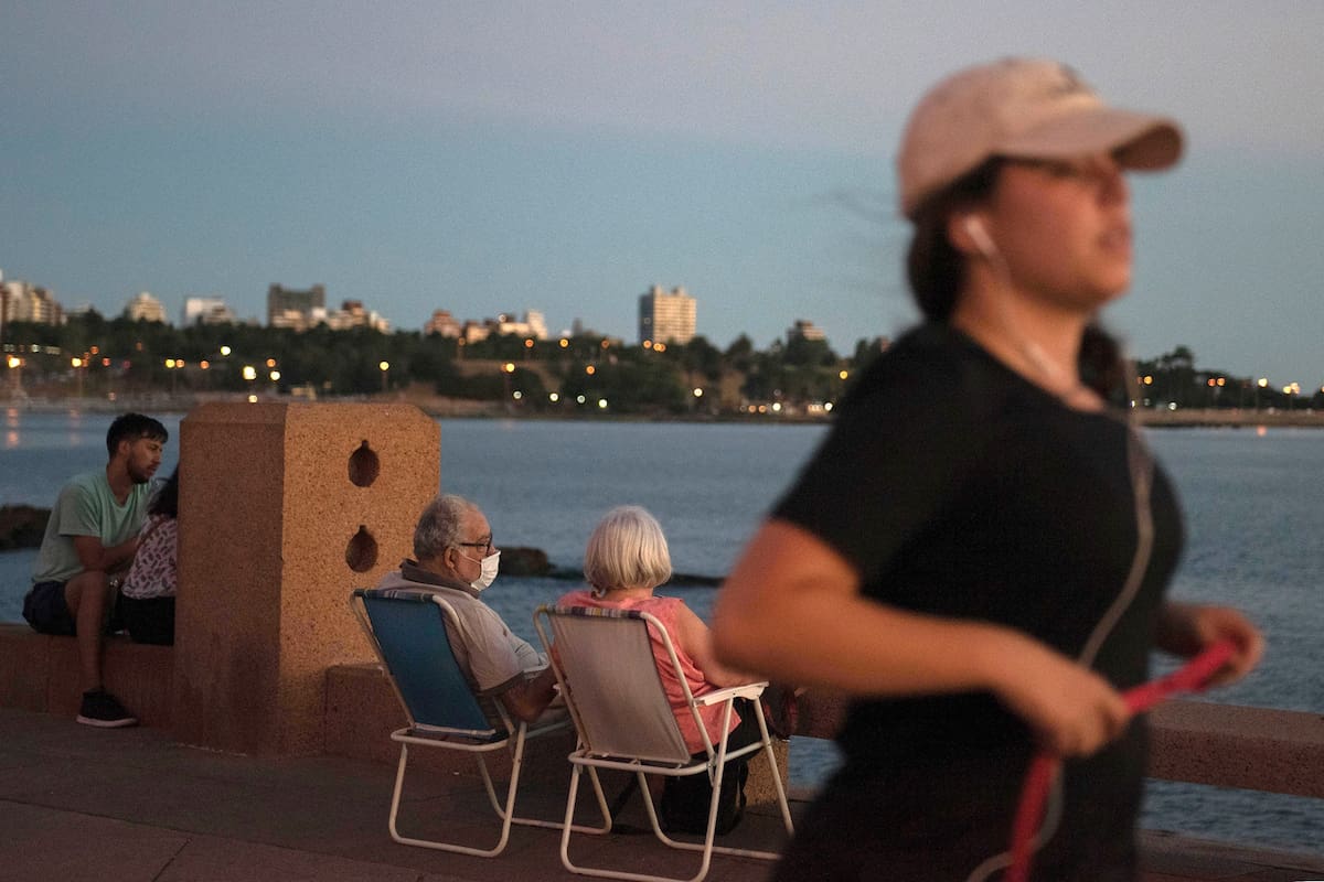 Una pareja de ancianos con barbijos disfruta el atardecer en Montevideo.