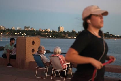 Una pareja de ancianos con barbijos disfruta el atardecer en Montevideo.