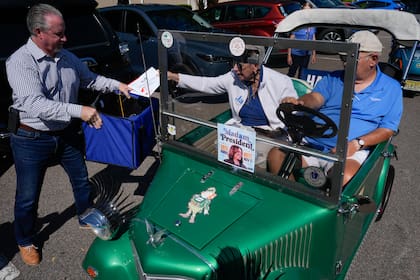 Una pareja deposita sus votos por correo en la urna sostenida por el supervisor electoral del condado Sumter, Bill Keen, en The Villages, Florida, el 14 de octubre de 2024. (Foto AP/Rebecca Blackwell)