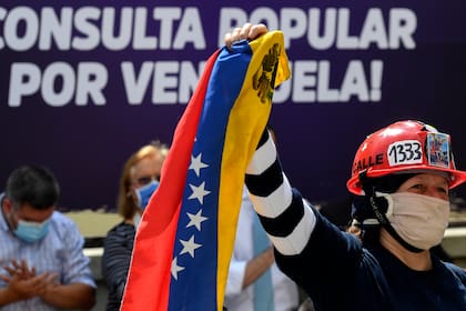 Una partidaria del líder opositor venezolano Juan Guaidó sostiene una bandera venezolana mientras pronuncia un discurso para cerrar la campaña para una consulta popular en Caracas el 11 de diciembre de 2020