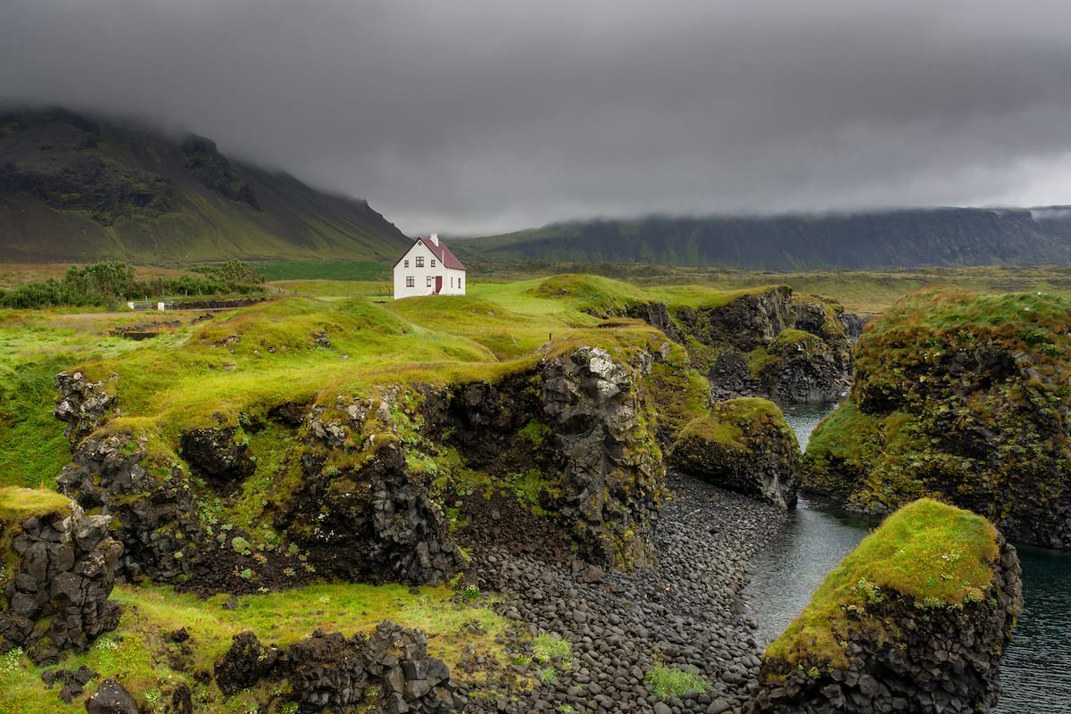 Una pequeña cabaña en Arnarstapi, Islandia, se encuentra en la base de una montaña.