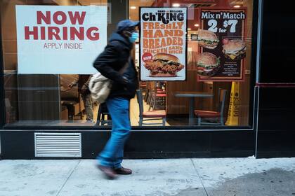 Una persona camina junto a un cartel que anuncia empleo en un restaurante de comida rápida en Nueva York