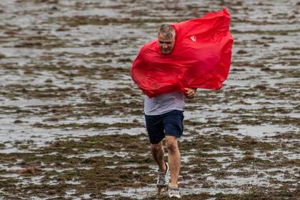Una persona camina sobre el suelo expuesto de la bahía de Tampa debido a la marea baja y los intensos vientos generados por el huracán Ian (Willie J. Allen Jr./Orlando Sentinel vía AP)