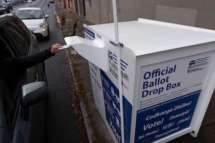 Una persona deposita una boleta en un buzón electoral afuera de las oficina de la División Electoral del condado Multnomah, en Portland, Oregon, el lunes 28 de octubre de 2024. (AP Foto/Jenny Kane)