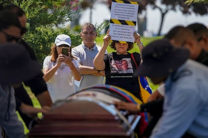 Una persona muestra un cartel de protesta durante el entierro del exteniente venezolano Ronald Ojeda en el cementerio Canaan en Santiago, Chile, el 8 de marzo de 2024.