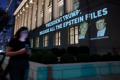 Una persona pasa junto a una imagen del presidente estadounidense Donald Trump y Jeffrey Epstein, junto con el mensaje "Presidente Trump: Libere todos los archivos de Epstein", proyectada sobre la sede del Departamento de Comercio de EE. UU. el 18 de julio de 2025 en Washington, D.C.