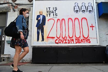 Una persona pasa junto al arte callejero del artista "Pure.Genius" el 2 de octubre de 2020 en el distrito de Brooklyn de la ciudad de Nueva York