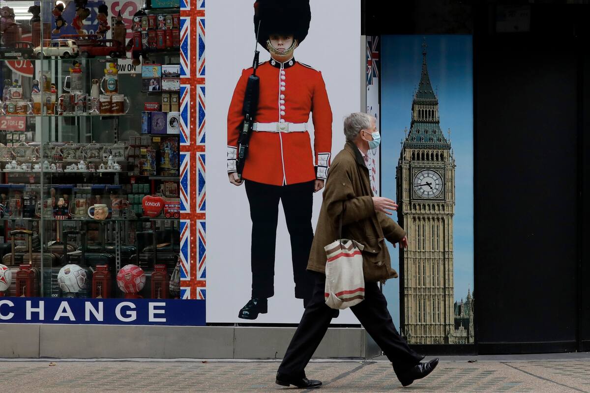 Una persona que lleva una mascarilla pasa junto a una tienda de souvenirs cerrada temporalmente en Oxford Street, durante el segundo bloqueo por coronavirus en Inglaterra, en Londres