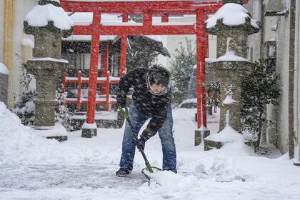 Una persona retira con una pala la nieve de la entrada a un santuario el miércoles 25 de enero de 2023 en Tottori, prefectura de Tottori, en el oeste de Japón. La nieve y el frío afectaban a buena parte de Japón el miércoles y complicaban los desplazamientos, con previsiones de más nevadas y bajas temperaturas. (Kyodo News via AP)