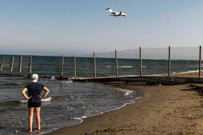 Una persona se para en la orilla del mar mientras un avión desciende hacia el Aeropuerto Internacional de Larnaca de Chipre