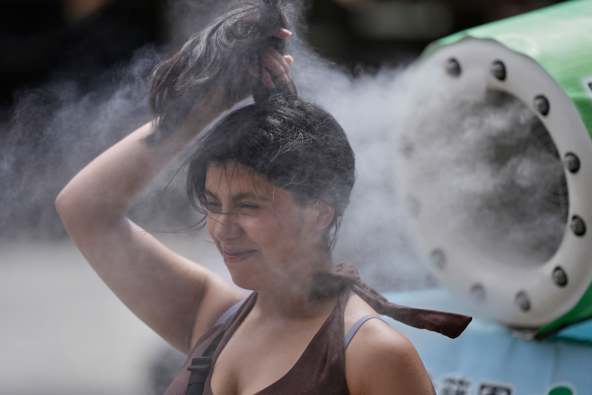 Una persona se refresca en una unidad de enfriamiento durante un caluroso día en el templo budista S
