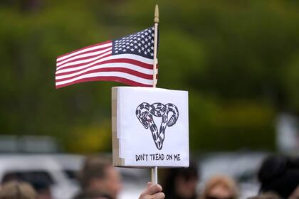 Una persona sostiene un letrero que dice: "No me pisotees" con una serpiente en forma de útero y una bandera de Estados Unidos, el martes 3 de mayo de 2022, durante un evento en un parque de Seattle para apoyar el derecho al aborto. (AP Foto/Ted S. Warren)