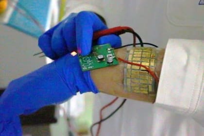 Una persona usando el sistema eléctrico autoalimentado compuesto por una banda flexible TEG y un LED