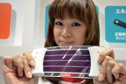 Una promotora muestra un prototipo de control remoto flexible del fabricante Murata, fabricado con un sensor basado en un film orgánico transparente que detecta el comportamiento del usuario