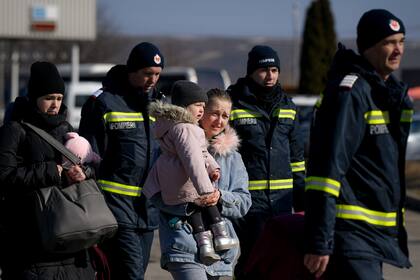 Una refugiada que huye de la guerra desde la vecina Ucrania carga a un niño tras cruzar la frontera con Rumanía, el lunes 14 de marzo de 2022, en Siret, Rumania. (AP Foto/Andreea Alexandru)