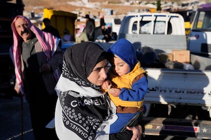 Una refugiada siria carga a su hijo en brazos mientras se prepara para volver a su país dentro de una operación de regreso voluntario, en la localidad fronteriza de Arsal, en el este de Líbano, el martes 14 de mayo de 2024.