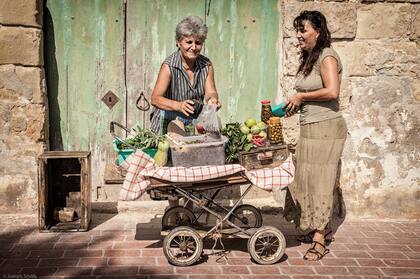 "Una señora vende alcaparras y otras delicias en su viejo carrito en las calles de Marsaxlokk, un pueblo de pescadores en Malta"