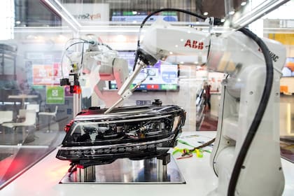 Una serie de brazos robóticos en exposición ponen a prueba los faros de un vehículo en una exposición de robots industriales en Brno, la segunda ciudad más grande de República Checa