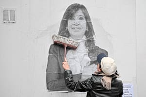 Una simpatizante de la expresidenta argentina Cristina Fernández de Kirchner pega un cartel frente a su residencia en Constitución