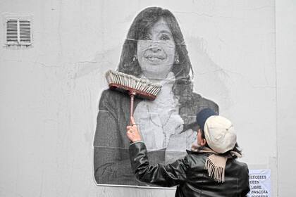 Una simpatizante de la expresidenta argentina Cristina Fernández de Kirchner pega un cartel frente a su residencia en Constitución