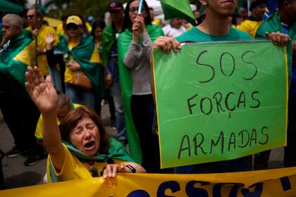 Una simpatizante del presidente Jair Bolsonaro reza durante una protesta contra la derrota del mandatario en la segunda vuelta de las elecciones presidenciales del país frente a una base militar de Sao Paulo, Brasil, el sábado 5 de noviembre de 2022. (AP Foto/Matias Delacroix)