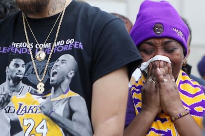 Una simpatizante parece rezar por Kobe Bryant, que estuvo omnipresente en la vestimenta de la gente: "Los héroes van y vienen. Las leyendas son viven para siempre", afirma la frase.
