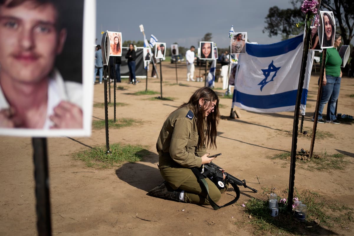 Una soldado israelí llora junto a un cartel que recuerda a una persona secuestrada por Hamas el 7 de octubre de 2023