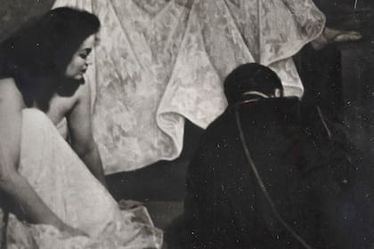 Una toma documental: Diego Rivera, echado en el suelo, da los últimos toques al retrato de la actriz María Félix, quien observa a su lado con curiosidad cómo pone su firma; la obra fue realizada en las Lomas de Chapultepec