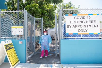 Una trabajadora de la salud se para en la entrada de un sitio de prueba de coronavirus en el Centro de Niños y Familias de San Juan Sano, el 24 de julio de 2020, en Los Ángeles, California