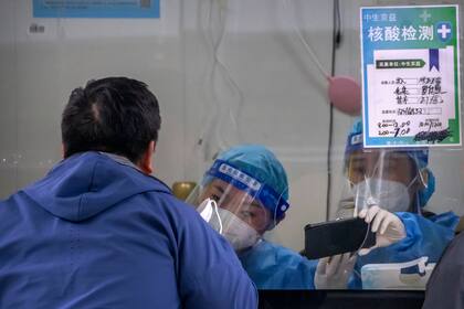 Una trabajadora, equipada con un traje de protección, realiza un test de detección del COVID-19 en un centro de pruebas en Pekín